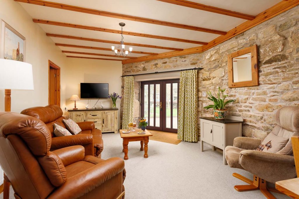 Living room area of The Roundhouse Cottage with brick walls and leather sofas